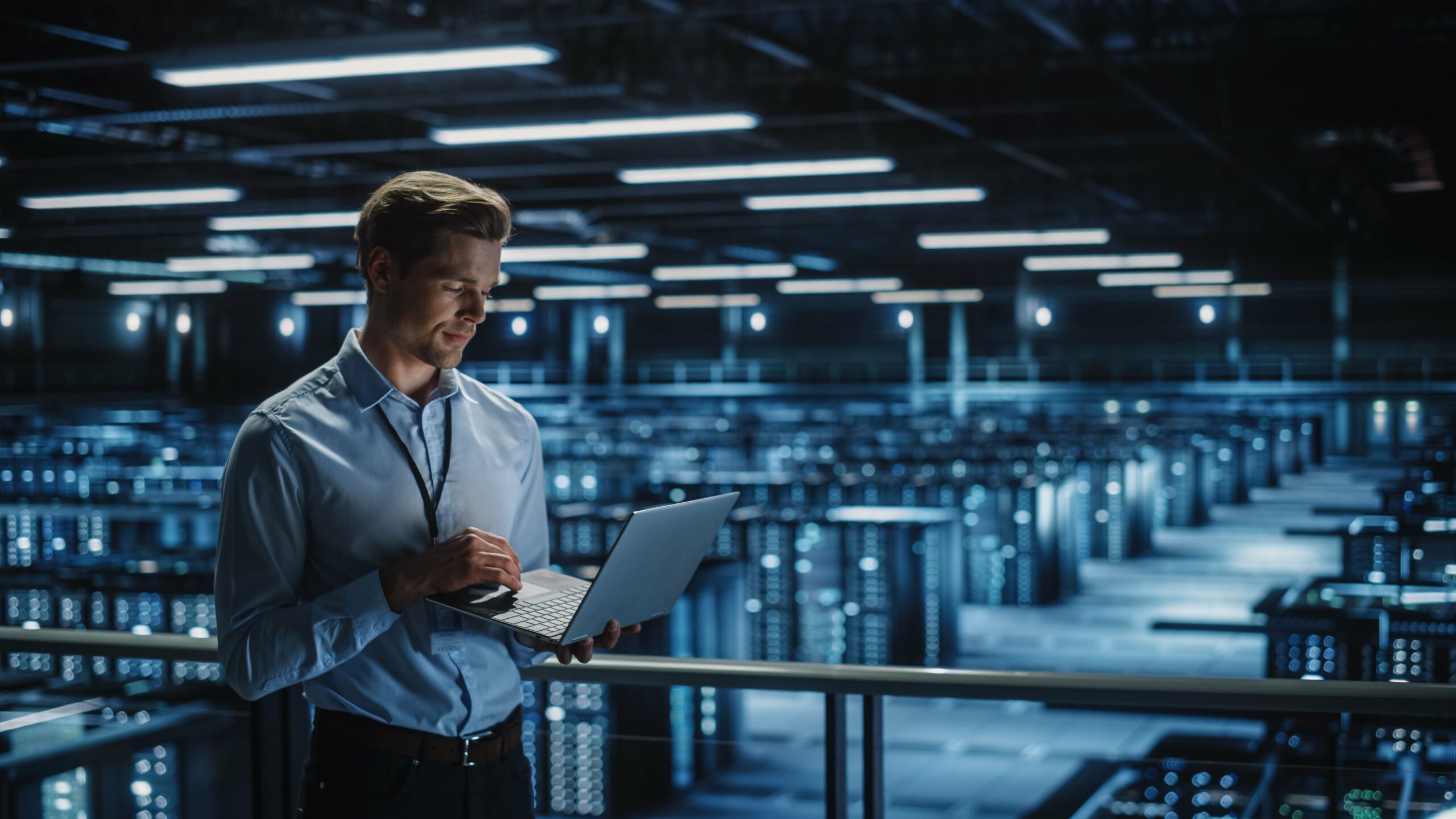 A man in a server room using advanced audit technology on his laptop