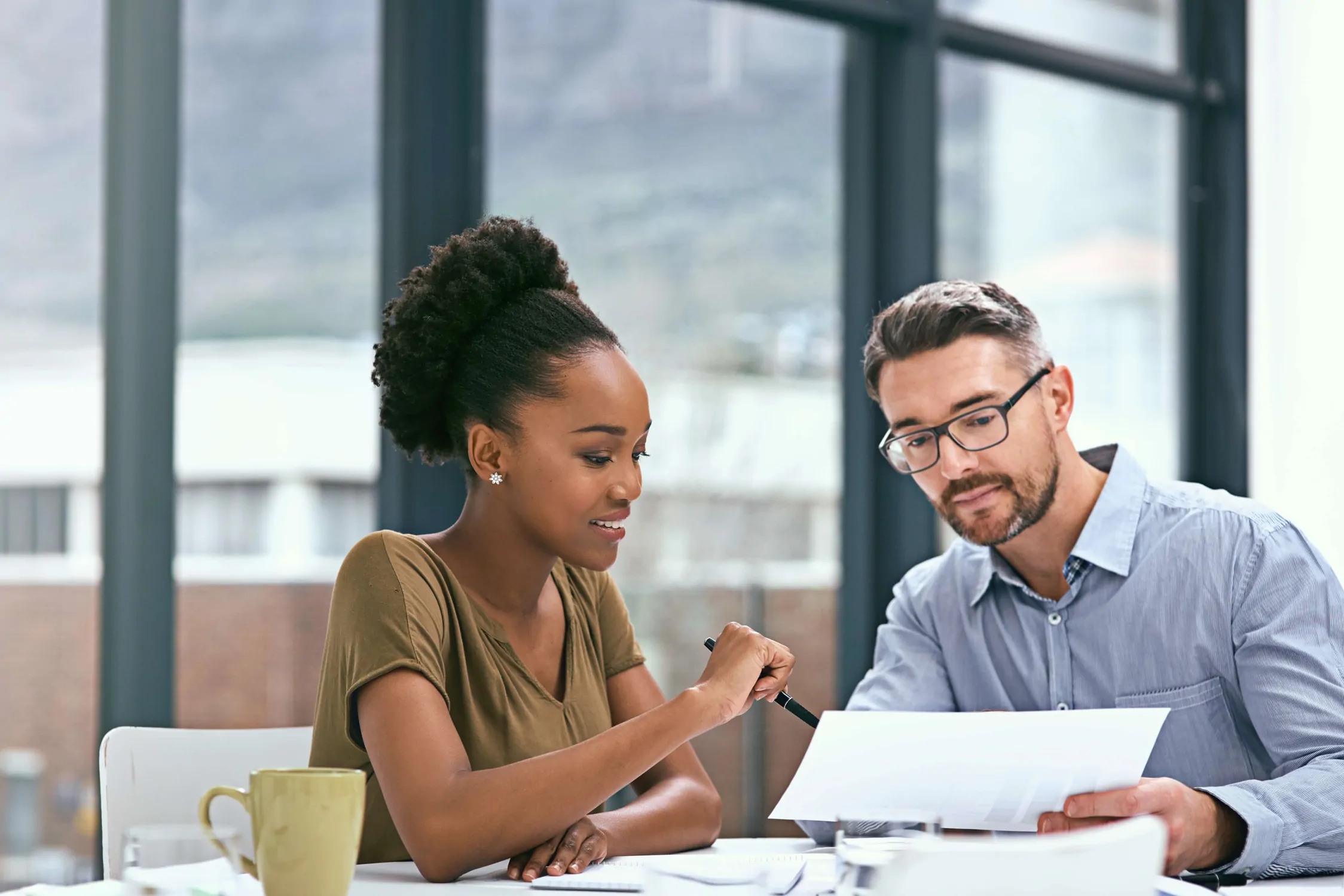 Co-workers at a meeting table discussing supplier contract audit and renegotiation plans