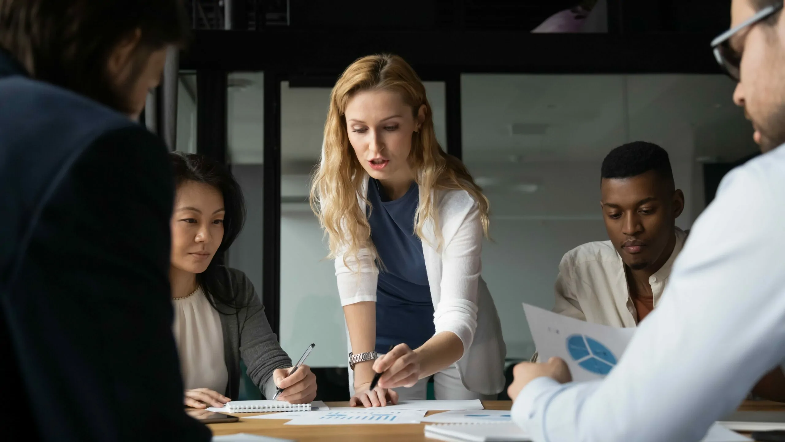 Person sitting at a meeting table viewing content with the person standing at the table.