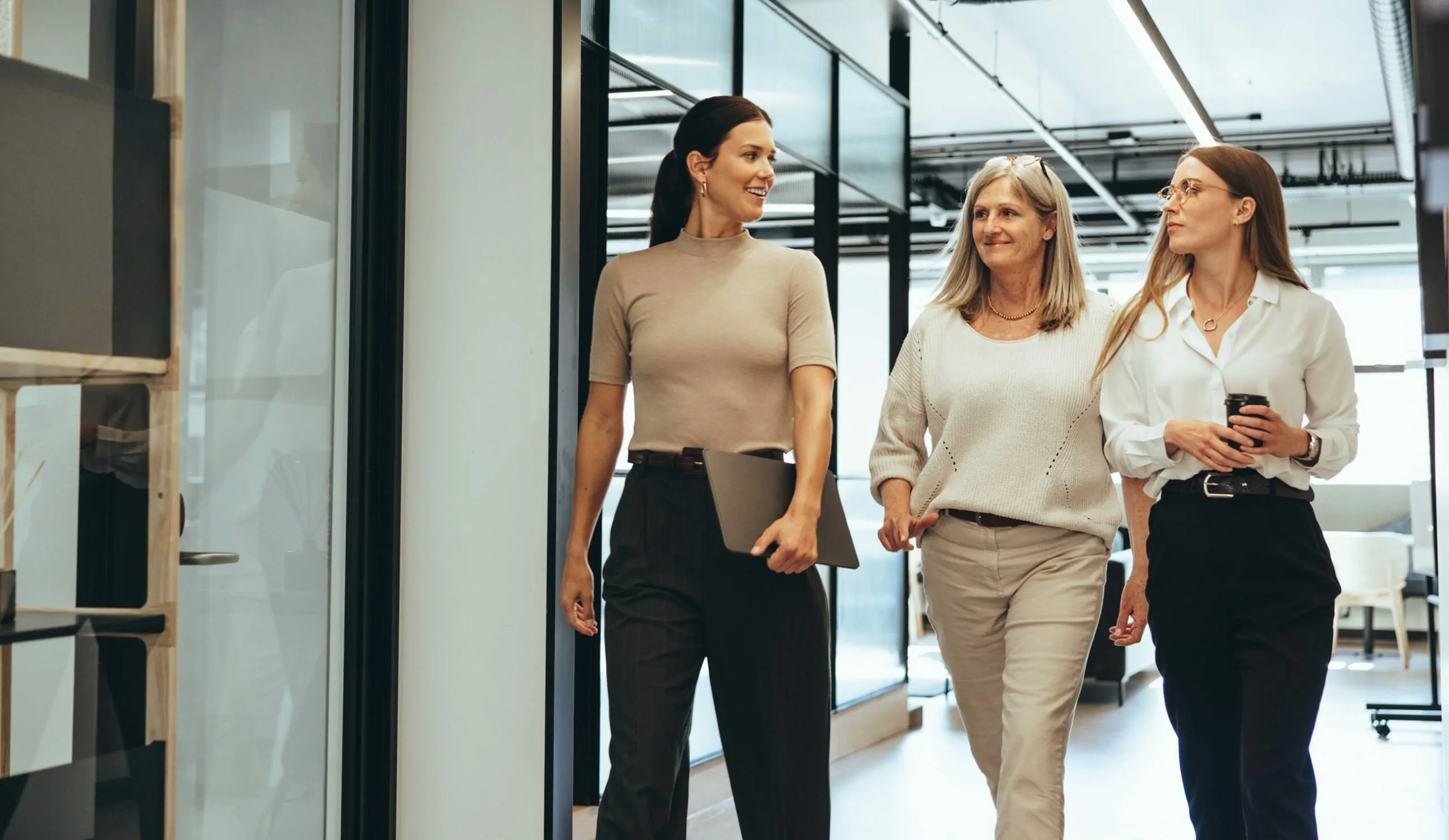 Three professionals walking into a meeting smiling and excited to present their vendor relationship management software insights.