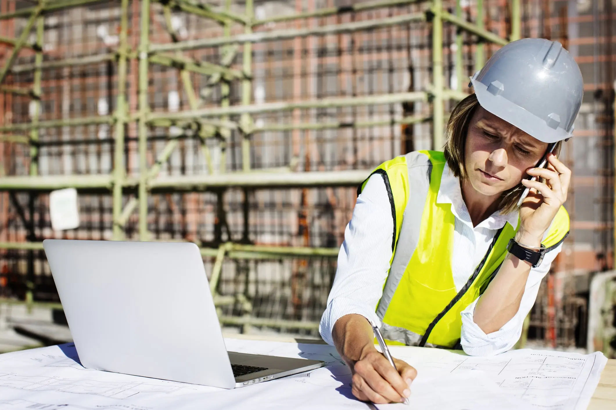 A female construction work talking on her cell phone and discussing contract compliance services with PRGX