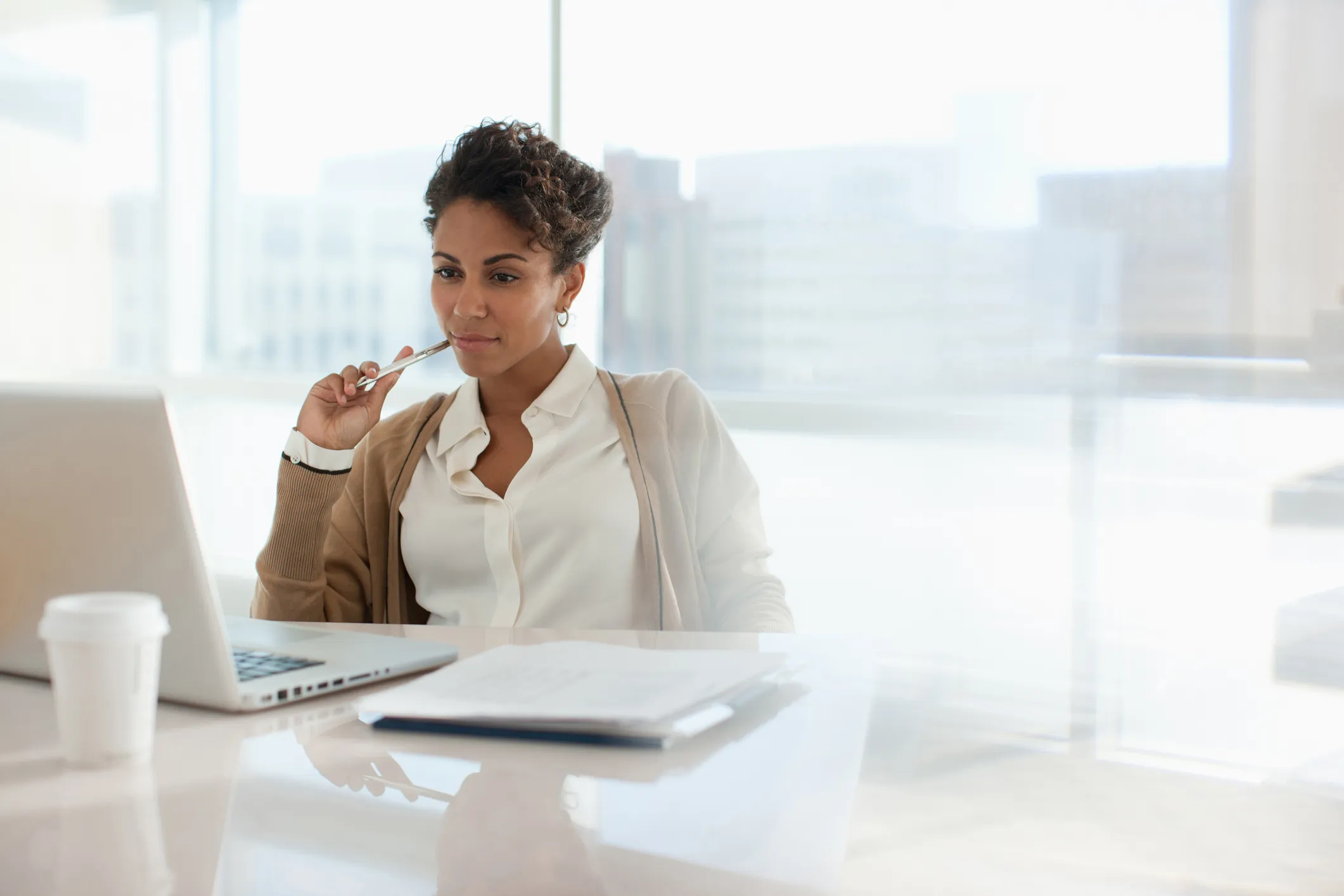 A professional women sitting at an office table reading the screen of her laptop about retail merchandise recovery software.